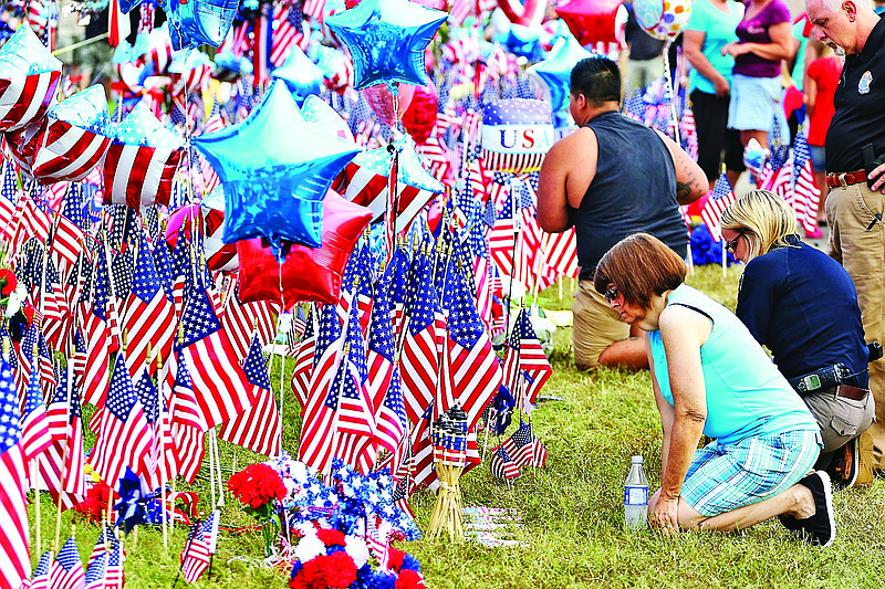 Charlene Jacobs, right, kneels to pay her respects on Monday, July 20, 2015, while at the Lee Highway memorial set up for last Thursday's Chattanooga shooting victims. Thaboua joined hundreds of others early Monday morning awaiting the possible arrival of Westboro Baptist Church members. Messages appearing to originate from the Westboro Baptist Twitter account indicated that the small church planned to picket the funerals of slain servicemembers killed in Chattanooga. The organization did not show up. 