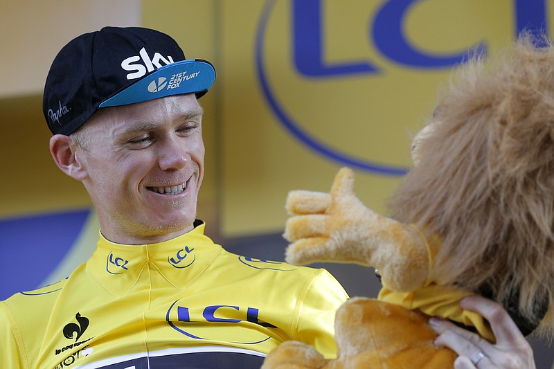 
              Britain's Chris Froome, wearing the overall leader's yellow jersey, is all smiles as he looks at the yellow jersey mascot equipped with a camera on the podium of the sixteenth stage of the Tour de France cycling race over 201 kilometers (124.9 miles) with start in Bourg-de-Peage and finish in Gap, France, Monday, July 20, 2015. (AP Photo/Christophe Ena)
            