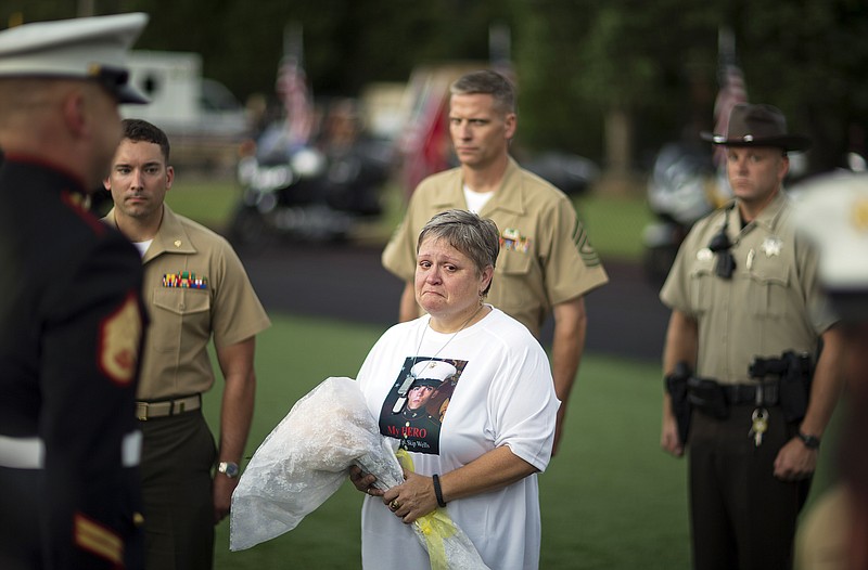 Cathy Wells, the mother of Lance Cpl. Squire Wells, known as "Skip," stands after being presented with flowers at a memorial service at Sprayberry High School, where Wells attended, Tuesday, July 21, 2015, in Marietta, Ga. Crowds gathered at the suburban Atlanta high school to remember the Marine who was fatally shot in an attack on military facilities in Chattanooga.