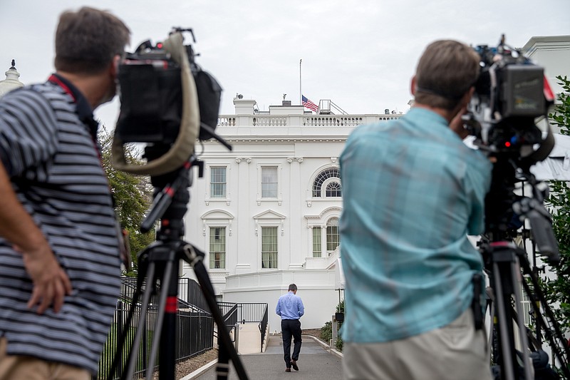 Members of the media film the American flag as it flies at half staff above the White House in Washington, Tuesday, July 21, 2015, to honor the five U.S. service members who were killed by a gunman in Chattanooga, Tenn. last week. President Obama has ordered flags at all military and federal buildings and grounds through out the United States to remain at half-staff through July 25th. (AP Photo/Andrew Harnik)
