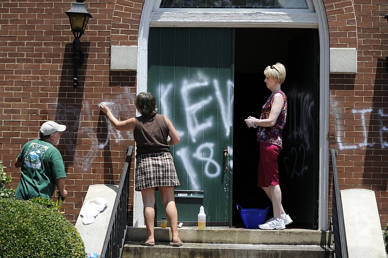 Mike Walraven, left, Robin Schweitzer, center, and Susan Charron clean the front of the Metropolitan Community Church of Our Redeemer in Augusta, Ga., Tuesday morning, July 21, 2015, after it was vandalized with graffiti overnight, in Augusta, Ga.