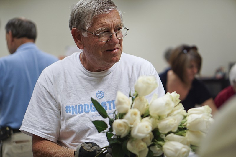 Moe Rivers works with other volunteers to prepare 3,000 roses at the City of Chattanooga's general services building on Wednesday, July 22, 2015, which will be used for upcoming memorial services. 