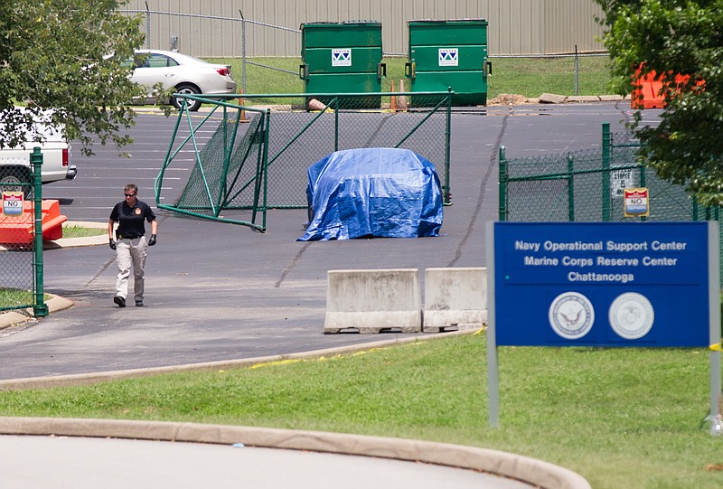 An investigator walks by the entrance of a Navy and Marine center in Chattanooga, Tenn., on Wednesday, July 22, 2015. Law enforcement officials for the first time provided details about how Muhammad Youssef Abdulazeez crashed the gates with his car and opened fire on the service members inspecting equipment there, killing four Marines and one sailor. (AP Photo/Erik Schelzig)