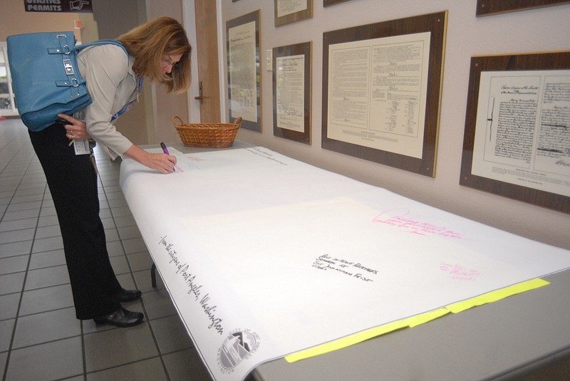 Debbie Hunt of Port Angeles, Wash., is one of the first to pen a message of condolence on a banner that will be sent to the city of Chattanooga offering sympathy after the shooting deaths of five military service members. The banner will made available for additional messages at Port Angeles City Hall through Friday.