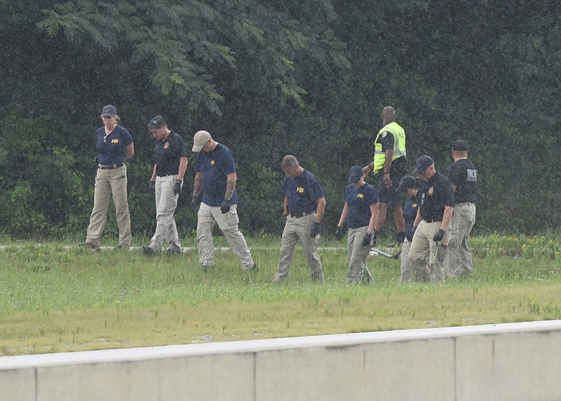 FBI investigators search a ditch at the Amnicola Highway exit ramp on northbound Highway 153 on Thursday, July 23, 2015, in Chattanooga, Tenn. FBI agent Jason Pack said the agency is following up on a lead in an ongoing investigation into two attacks on military installations in Chattanooga by a 24-year-old gunman who took this exit ramp on his way to fatally shoot four service members before falling in a hail of police gunfire.