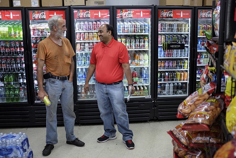 Owner Sunny Patel, right, talks with Paul Sutton in front of a drink cooler on Wednesday, July 22, 2015, at B&E Convenience Store in Dayton, Tenn. Following the July, 16 shootings in Chattanooga, a Facebook user in Dayton claimed that the owner of B&E Convenience had expressed joy at the news, but Patel, who is Hindu, says he was in Seattle, Wa., at the time and said no one in the store would have been joyful about the shootings.