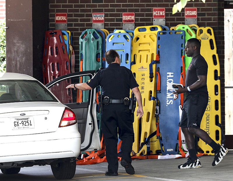 Sgt. DeMonte Cheeley is escorted to an unmarked patrol car by police officers from Erlanger Hospital's emergency room after a shooting at both the Amnicola Highway Armed Forces Career Center and the Naval Operational Support Center on Amnicola Highway on Thursday, July 16, 2015, in Chattanooga, Tenn. The shooting left five dead, including the shooter, and a Chattanooga police officer wounded.