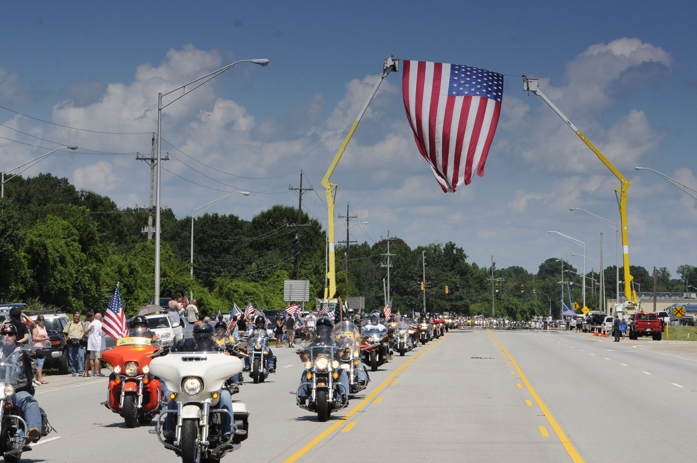 Hundreds of motorcycles pass under an American flag on Amnicola Highway several miles behind the front of the procession.