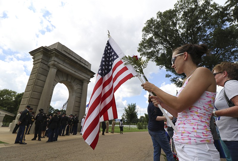 Kimberly Evans (28) from Chickamauga, Ga., holds her flag as people arrive for the burial service for U.S. Marine Staff Sgt. David Wyatt to begin at the Chattanooga National Cemetery on Friday, July 24, 2015. Wyatt was one of five servicemen whose death was the result of the second of two shootings carried out by Mohammad Youssuf Abdulazeez within a 30-minute span in Chattanooga, Tennessee, on July 16, 2015.