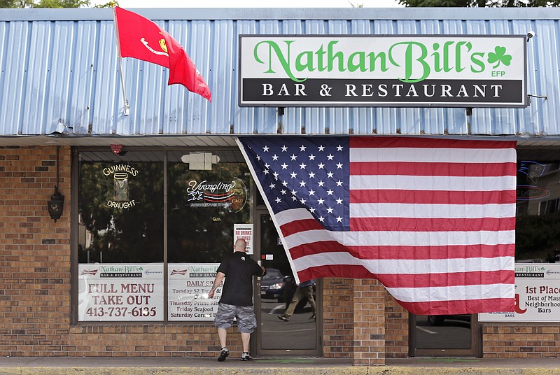 A patron walks under the U.S. Marine Corps and American flags while entering Nathan Bill's Bar & Restaurant, which is owned by the family of Gunnery Sgt. Thomas J. Sullivan, in Springfield, Mass., Friday, July 17, 2015.