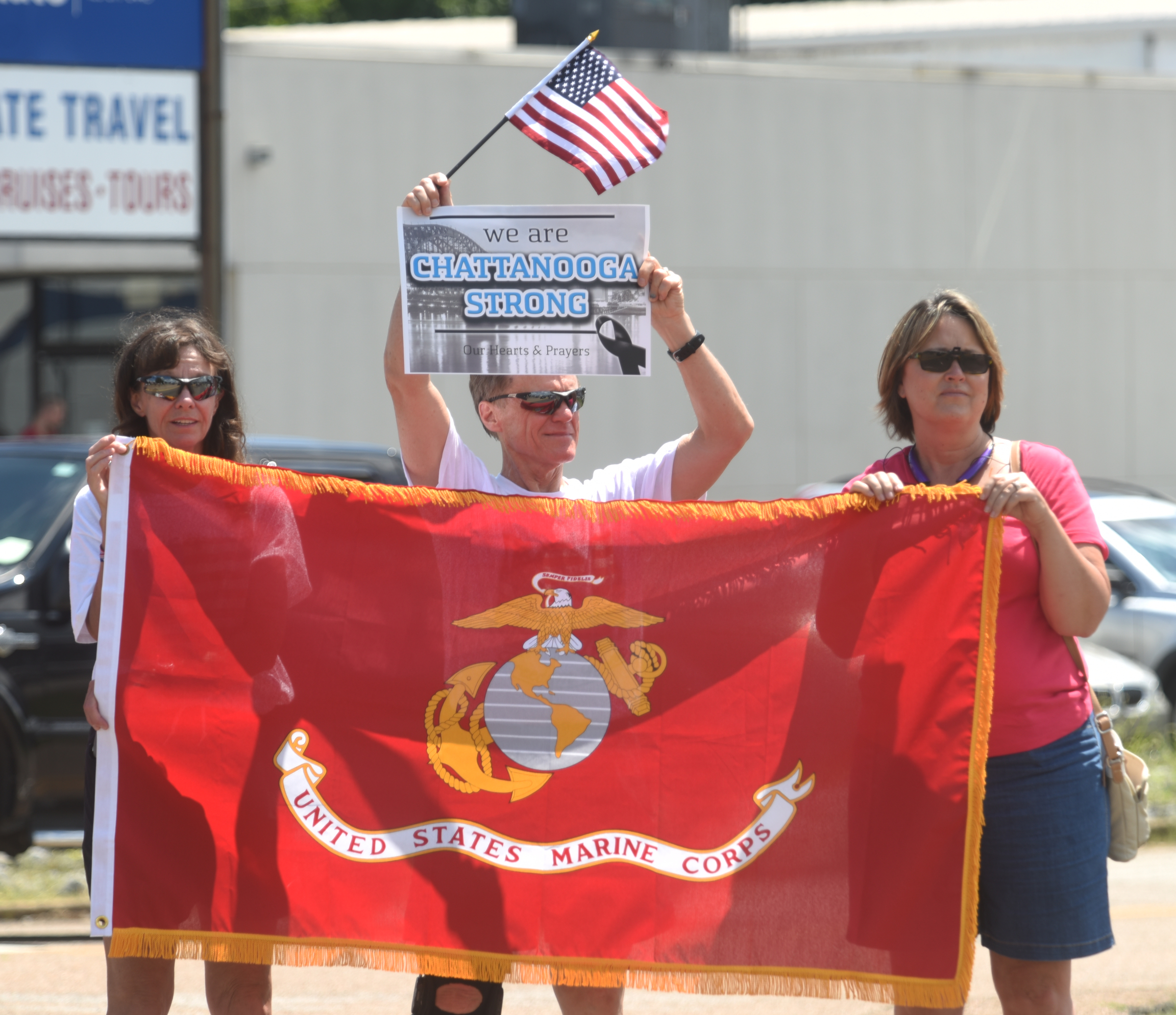 Debbie and Jerry Hightower and Dixie Pickett, from left, hold a Marine Corps flag as vehicles process down Highway 153 in Hixson after the funeral service for U.S. Marine Staff Sgt. David Wyatt.