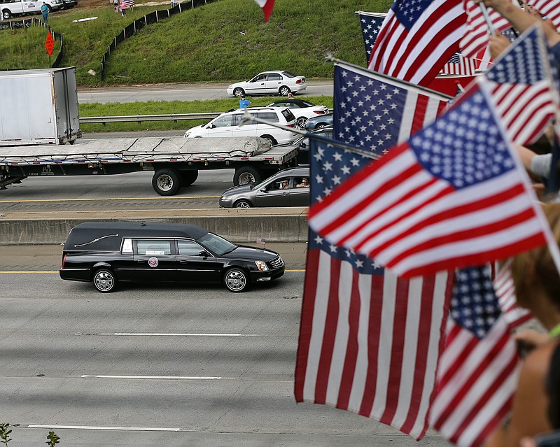 Onlookers hold flags as they pay respects to Lance Cpl. Squire 'Skip' Wells as procession carrying his remains approaches an overpass on I-75 in Marietta, Ga., Thursday, July 24, 2015. Wells was one of four Marines and sailor who were fatally shot in an attack on military facilities in Chattanooga, Tenn. 