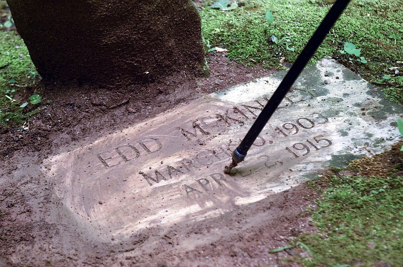 
              Retired National Park Service Ranger Arthur "Butch" McDade cleans the grave marker of 12-year-old Edd McKinley in the Great Smoky Mountains National Park on Wednesday, July 15, 2015, near Gatlinburg, Tenn. McKinley, a runaway who froze to death in the mountains in 1915, laid in an unmarked grave until 1975 when a chance encounter brought closure to the boy's family.  (Adam Lau/Knoxville News Sentinel via AP)
            