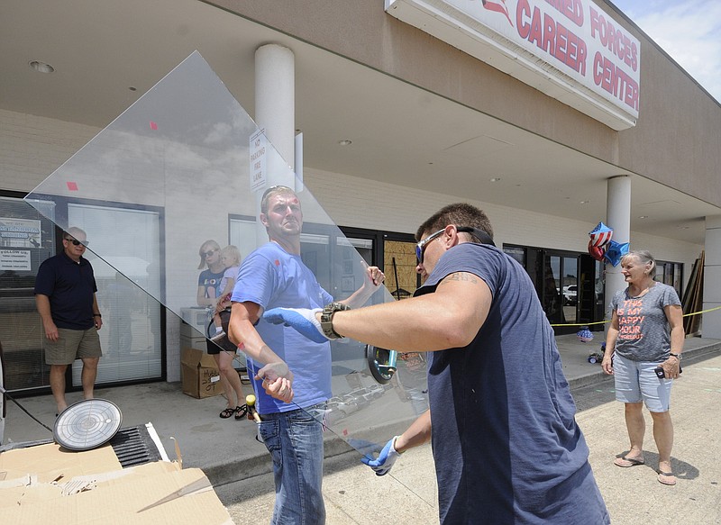 Hubbuch Glass employee's Bradley Crow, left, and Jason McClain begin replacing the glass Monday fronting the Armed Forces Career Center where multiple bullet holes once were visible. The center was one of the scenes of a deadly shooting spree in Chattanooga on July 16. Crow said they were replacing six doors and two side lights.