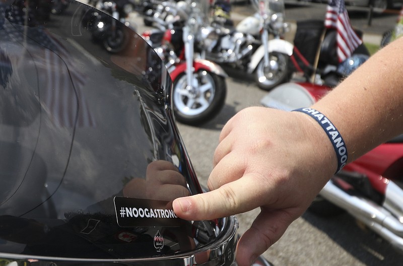 Chattanooga resident Chris Gordon applies a "NoogaStrong" sticker to his motorcycle before the funeral service for Petty Officer 2nd Class Randall Scott Smith commences on July 28, 2015 at the First Baptist Church in Fort Oglethorpe, Ga. Scott was one of five servicemen whose death was the result of a series of shootings at military facilities in Chattanooga, Tennessee, on July 16, 2015.