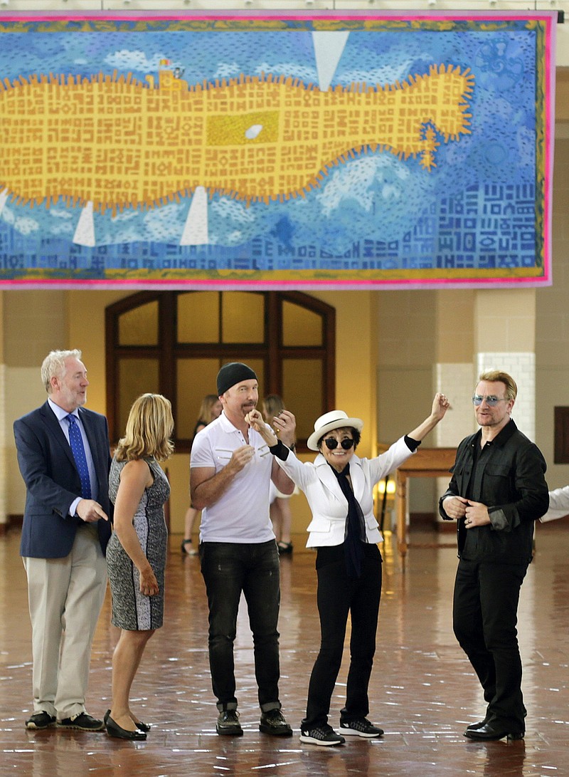 
              Yoko Ono, widow of John Lennon, second right, reacts after the unveiling of a 24' x 10' tapestry depicting the island of Manhattan as a yellow submarine piloted by a waving John Lennon at Ellis Island Wednesday, July 29, 2015, in New York. Standing with Ono are Bono, right, and The Edge, of the Irish rock band U2, third from right.  (AP Photo/Frank Franklin II)
            