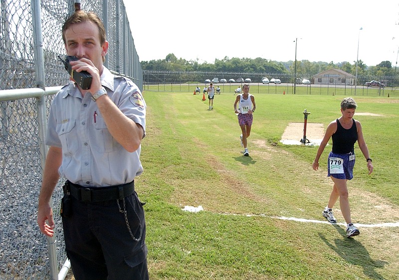 Lawrence Kemp, left, a correctional officer at the Middle Tennessee Correctional Complex in Nashville, Tenn., guards a gate as marathon runners pass by in the recreation yard on Wednesday, Sept. 17, 2003. Runners from area running clubs joined inmates for several different runs in the prison yard during the "Jaunt in the Joint."