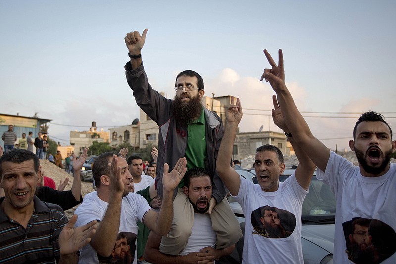 
              FILE - In this Sunday, July 12, 2015, file photo, Palestinian Khader Adnan, center, who recently ended a 55-day hunger strike, is greeted by Palestinians after his release from an Israeli prison in the West Bank village of Arrabeh near Jenin. Israel's parliament passed a contentious law on Thursday that would permit the force-feeding of inmates on hunger strike, eliciting harsh criticism over the practice. (AP Photo/Majdi Mohammed, File)
            