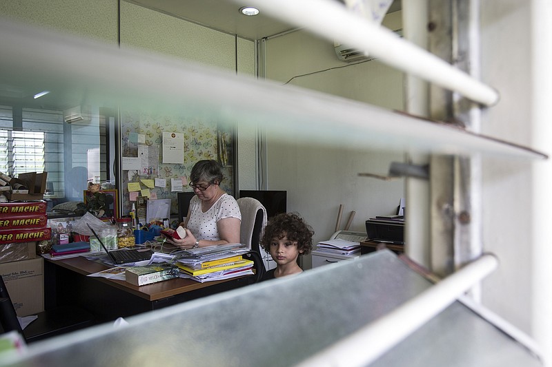 Jacquita Gomes, 53, left, accompanied by her grandson, Raphael Ariano, 4, checks her mobile phone at her office in Kuala Lumpur, Malaysia on Thursday, July 30, 2015.