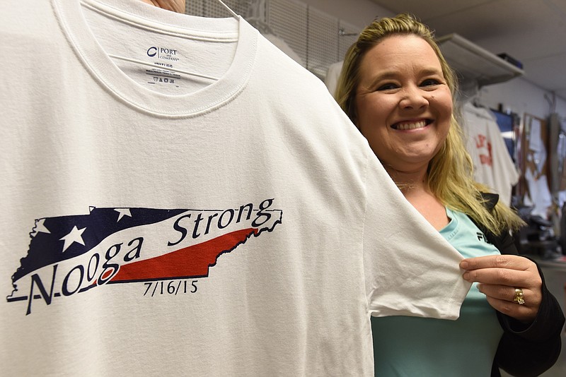 Kristi Manning, co-owner of Carter Shooting Supply & Range on Highway 58, holds a Nooga Strong t-shirt in the store Friday, July 31.