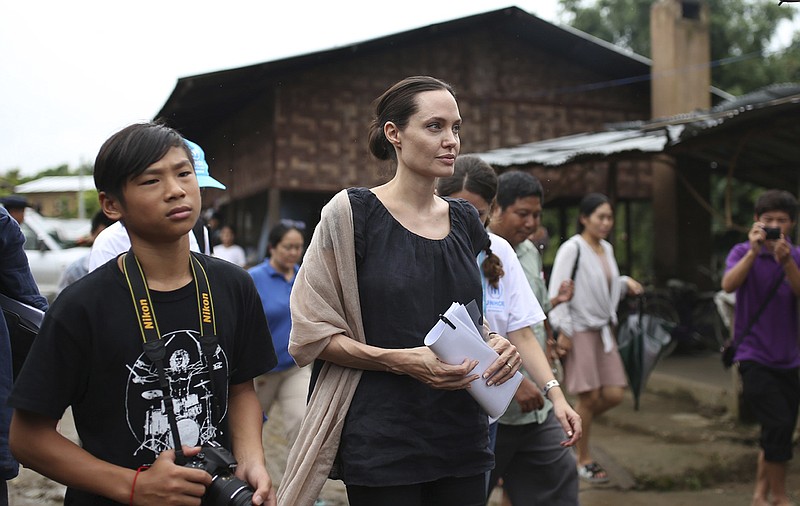 
              CAPTION CORRECTION, CORRECTS NAME OF ANGELINA JOLIE'S SON TO PAX - Actress Angelina Jolie Pitt, United Nations High Commissioner for Refugees special envoy and co-founder of the Preventing Sexual Violence Initiative, center, walks with her son Pax, left, as they visit Jan Mai Kaung refugee camp in Myitkyina, Kachin State, Myanmar, Thursday, July 30, 2015. The refugees have fled fighting between the Burmese government and the Kachin Independence Army since 2011. (AP Photo/Hkun Lat)
            