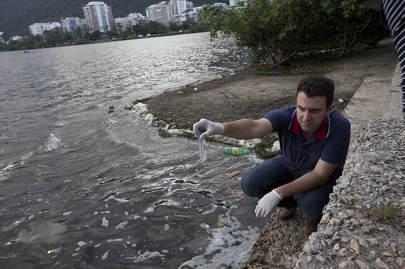 In this March 27, 2015 photo, Fernando Spilki, virologist and coordinator of the environmental quality program at Feevale University, holds a sample of water taken from the Rodrigo de Freitas Lake, in Rio de Janeiro, Brazil. The Associated Press commissioned the study of the virus and bacteria levels in the waters where Olympic athletes will compete next year in Rio de Janeiro. The testing found dangerously high levels of pathogens from human sewage waste. 