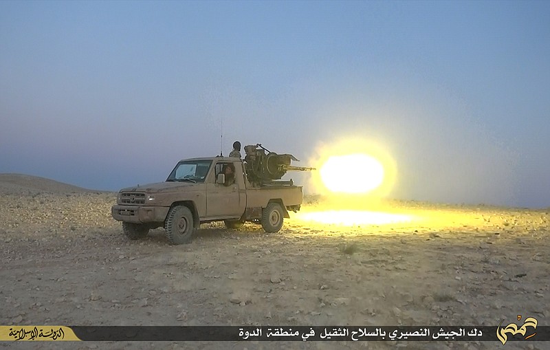 This picture released on July 12, 2015, by the Rased News Network, a Facebook page affiliated with Islamic State militants, shows an Islamic State militant fires a heavy weapon during a battle against Syrian government forces, in Homs province, Syria.