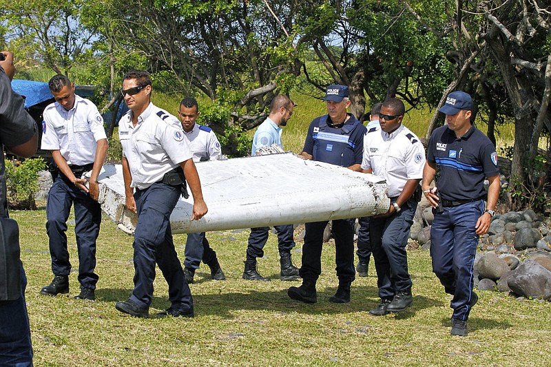 
              FILE - In this photo dated Wednesday, July 29, 2015, French police officers carry a piece of debris from a plane in Saint-Andre, Reunion Island. Malaysian officials said Sunday, Aug. 2, 2015 that they would seek help from territories near the island where a suspected piece of the missing Malaysia Airlines jet was discovered to try to find more possible debris from the plane. (AP Photo/Lucas Marie, File)
            