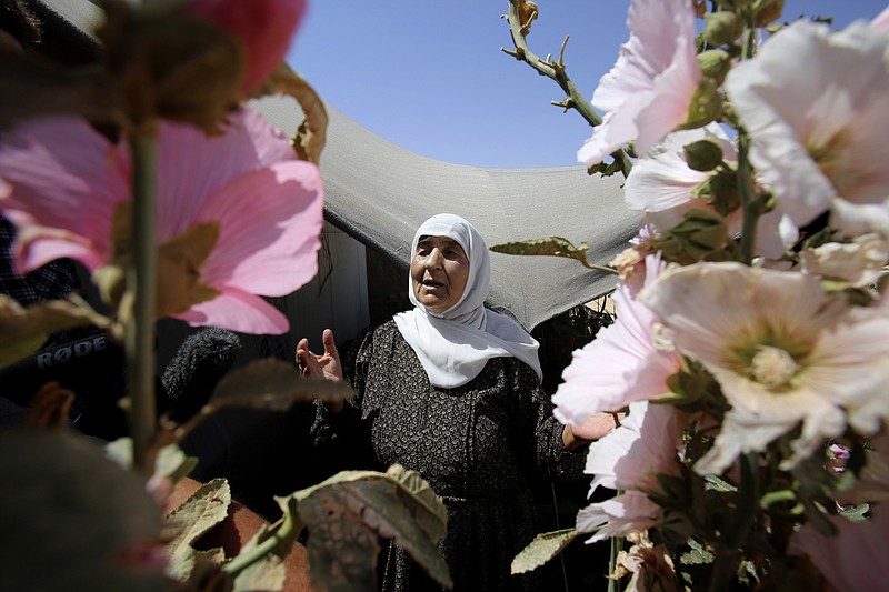 
              In this Wednesday, July 29, 2015 photo, an elderly Syrian refugee woman stands outside her shelter surrounded with flowers she planted, at Zaatari refugee camp, in Mafraq, Jordan. On Zaatari’s anniversary this past week, the transformation from tent camp to city symbolizes the failure of rival world powers to negotiate an end Syria’s war. But some say it’s also a reminder that the shift from emergency aid to long-term solutions, such as setting up a water network to replace expensive delivery by truck, should have come much sooner. (AP Photo/Raad Adayleh)
            