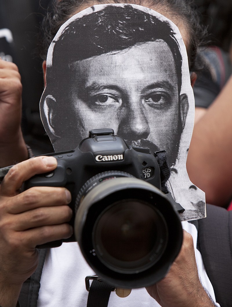 
              A photojournalist protests the murder of photojournalist Ruben Espinosa Becerril as he holds a printout of his photo, in Mexico City, Sunday, Aug. 2, 2015. Espinosa, 31, who worked for the investigative magazine Proceso and other media was found murdered along with 4 women, in an apartment in a middle-class neighborhood of Mexico City, where he had fled because of harassment in the state he covered. (AP Photo/Marco Ugarte)
            