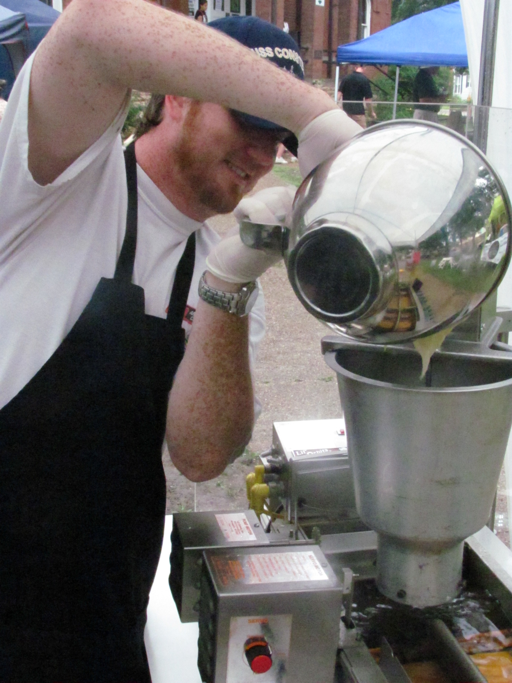 Kris Spengler, co-owner of Monkey Town Donuts, pours batter into a 300-dozen per hour donut maker during the 24th annual Scopes Heritage Festival in Dayton, TN.
