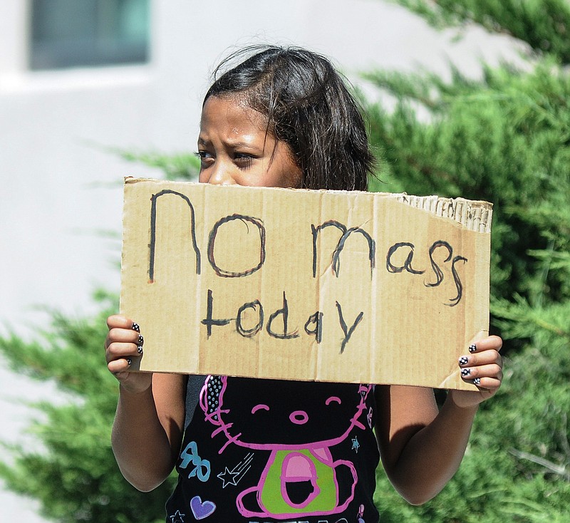 
              Aaliyah Doninguez, 11, stands on N. Alameda Boulevard on Sunday, Aug. 2, 2015, in Las Cruces, N.M., advising parishioners that Holy Cross Catholic Church mass is canceled. Churchgoers were left shaken during Sunday morning services after authorities say explosions occurred less than 30 minutes apart outside two Las Cruces churches. (Robin Zielinski/The Las Cruces Sun-News via AP) MANDATORY CREDIT
            