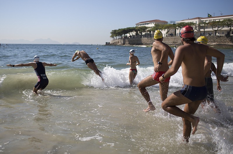 
              Triathlon athlete Kevin Mcdowell, left, of the U.S., and local swimmers enter the water for a swimming clinic along Copacabana beach in Rio de Janeiro, Brazil, Monday, Aug. 3, 2015. Triathletes swam in waters off Copacabana Beach despite published warnings that water in the area was "unfit" for swimming. On Thursday, The Associated Press released the results of a five-month investigation that showed that Olympic venues are rife with disease-causing viruses and bacteria. (AP Photo/Leo Correa)
            