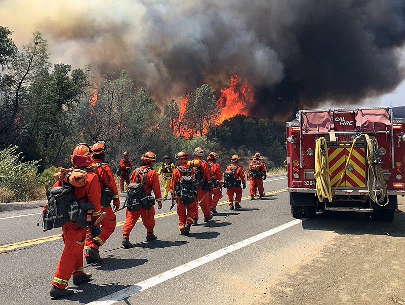 
              Fire crews walk on U.S. Highway 20 as a fire approaches near Clearlake, Calif., Monday, Aug. 3, 2015. Cooler weather helped crews build a buffer Monday between a raging Northern California wildfire and some of the thousands of homes it threatened as it tore through drought-withered brush that hadn't burned in years. (AP Photo/Terry Chea)
            