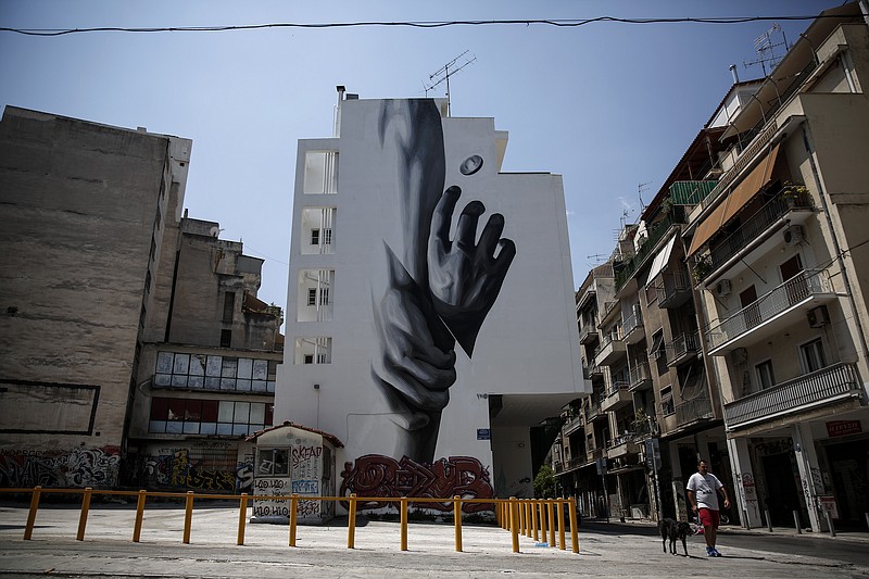 
              A man walks with his dog past a mural at a central neighborhood in Athens, Greece, on Sunday, Aug. 2, 2015. In Athens, the heads of the EU-IMF audit mission met with the Greek ministers of finance and economy with the talks focusing on bank recapitalisation, privatisations and fiscal targets, the finance ministry said.  (AP Photo/Yorgos Karahalis)
            