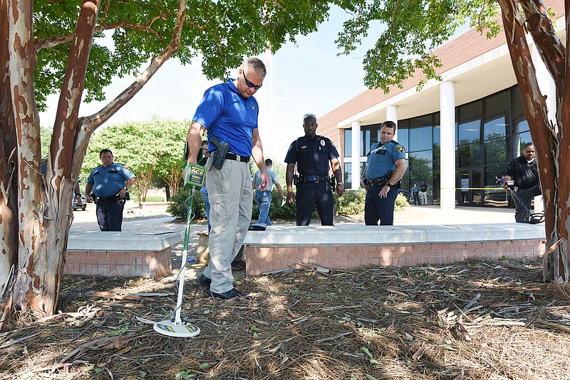 Investigators search for a shell casing along the perimeter of a pedestrian plaza outside the Madison County Courthouse in Canton, Miss., after a shooting on Monday, Aug. 3, 2015. A man fatally shot a defendant waiting in a small courtyard outside the county courthouse. A suspect is in custody, law enforcement officials said.
