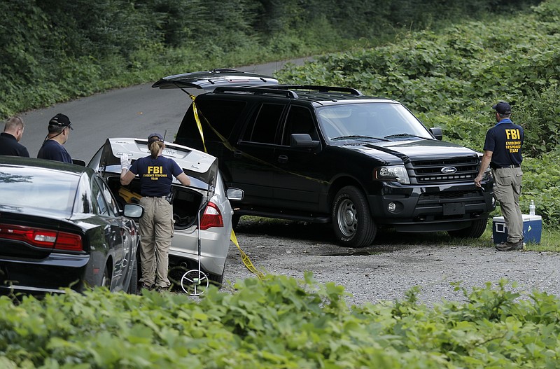 Investigators with the FBI Evidence Response Team and NCIS search a pull-off along the Tennessee River from River Canyon Road on July 30 in Chattanooga, Tenn.