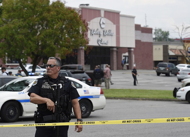 An officer stands in front of the Carmike Hickory 8 movie theater following a shooting Wednesday, Aug. 5, 2015, in Antioch, Tenn. A suspect wielding a hatchet and a gun inside the Nashville-area movie theater died after exchanging gunshots with a SWAT team that stormed the theater, police said. (AP Photo/Mark Zaleski)