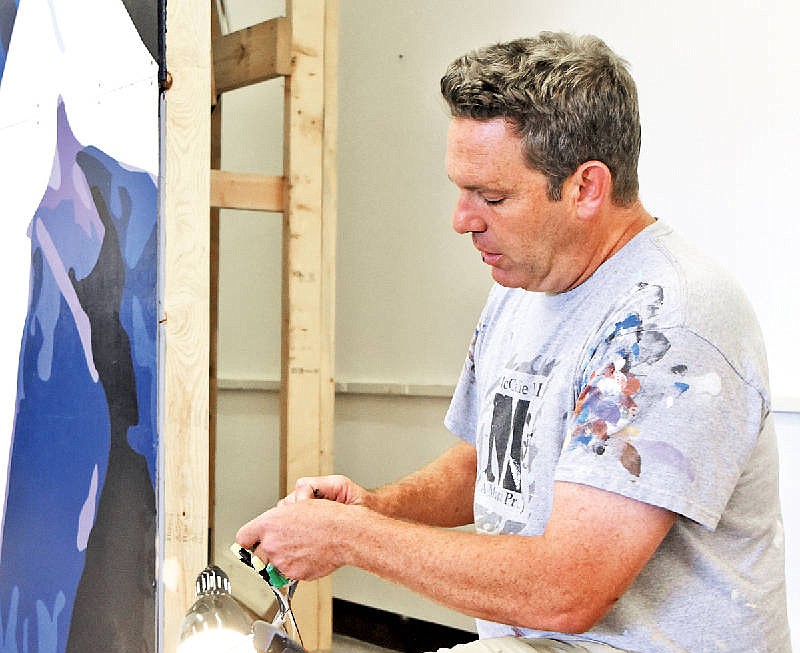 Kevin Bate works to install a piece of artwork at the Chattanooga Public Library on Tuesday. He will soon begin portraits of the four Marines and one sailor who were killed in an attack last month.