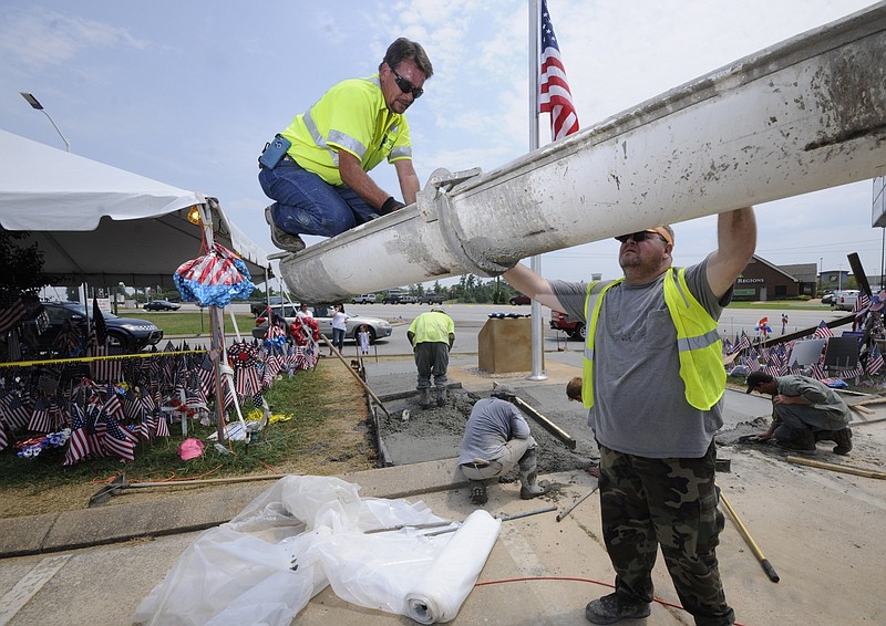 Sequatchie Concrete Service employee's David Dean, top, and William Adams work to clean excess concrete after pouring five-yards of the mix at the Lee Highway Memorial built for five servicemen that were slain by a gunman in July.