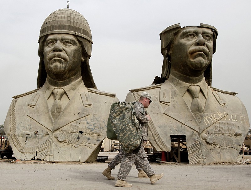 
              FILE - In this March 20, 2009, file photo, U.S. Army soldiers stroll past two bronze busts of former Iraqi President Saddam Hussein in the Green Zone in Baghdad, Iraq. Under its leader, Iraqi jihadi Abu Bakr al-Baghdadi, the Islamic State group's top command is dominated by former officers from Saddam's military and intelligence agencies, according to senior Iraqi officers and top intelligence officials. (AP Photo/Hadi Mizban, File)
            