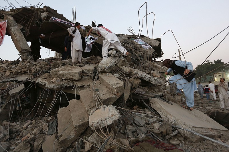 Afghan boys climb on debris of a market destroyed in Friday's bomb attack at the site of a truck bomb attack in Kabul, Afghanistan, Saturday, Aug. 8, 2015. The bombing attack in a residential area of Kabul killed over 10 people and wounded more than 200, in one of the most devastating attacks on the capital since the insurgency began in 2001.