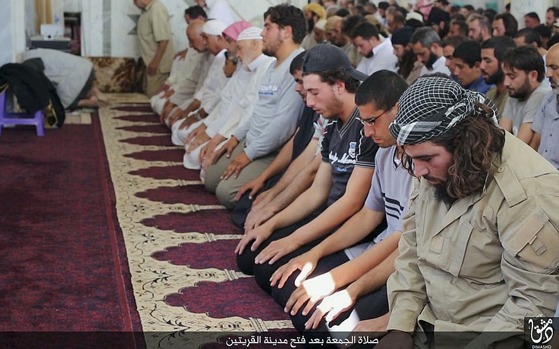 
              In this photo provided Friday, Aug. 7, 2015, by the Rased News Network, a Facebook page affiliated with Islamic State militants, Muslim worshipers attend Friday prayers in a mosque in the central Syrian town of Qaryatain. The Arabic on the bottom banner reads, "Friday prayers after the conquest of Qaryatain." Activists on Saturday said hundreds of families fled the Christian town of Sadad as Islamic State militants captured Qaryatain on Thursday, which is about 25 kilometers (15 miles) northwest of Sadad. (Rased News Network, a Facebook page affiliated with Islamic State militants via AP)
            