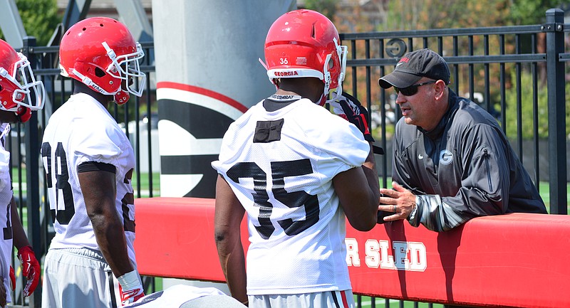 Georgia redshirt sophomore cornerback Aaron Davis (35), shown here listening to defensive coordinator Jeremy Pruitt during practice last week, is among several Bulldogs players wearing GPS units this month in preseason camp.
