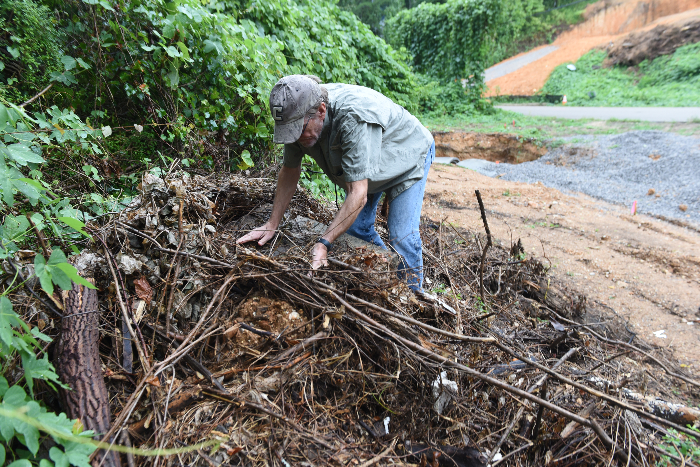 Dr. Nick Honerkamp of the UTC archeology department removes brush from an entrance marker at the site of an old cemetery located next to the construction site for a new housing development on Dartmouth Street in the North Chattanooga community Monday, Aug. 10, 2015, in Chattanooga, Tenn.