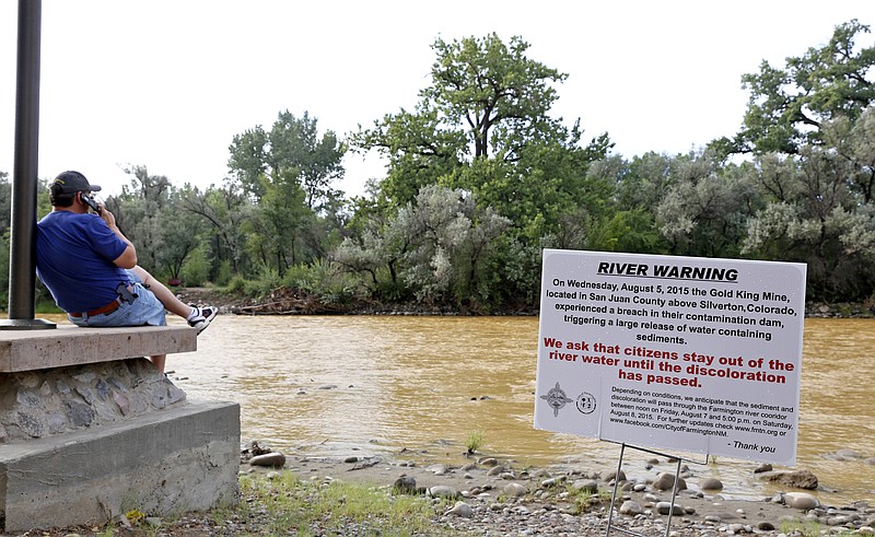 A warning sign from the city is displayed in front of the Animas River as orange sludge from a mine spill upstream caused by the Environmental Protection Agency flows past Berg Park in Farmington, N.M., last week.