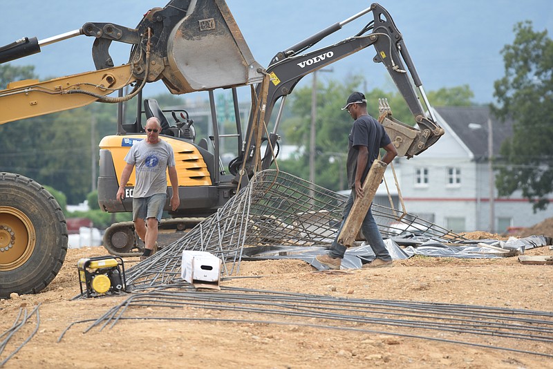 Sculptor Peter Lundberg, left, assisted by Desmond Lewis, lowers a form made of rebar into a trench as they work on a project at the Sculpture Field at Montague Park on Monday, Aug. 10, 2015, in Chattanooga, Tenn. Lundberg plans to lift the 60 foot sculpture using a crane on Sept. 1. 