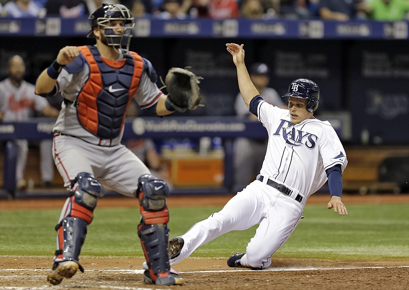 Tampa Bay Rays' Brandon Guyer, right, scores ahead of the throw to Atlanta Braves catcher A.J. Pierzynski on an error by Braves' Joey Terdoslavich during the seventh inning of a baseball game Wednesday, Aug. 12, 2015, in St. Petersburg, Fla. 