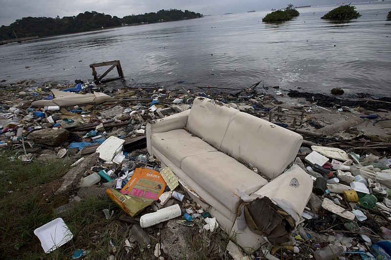 In this June 1, 2015, file photo, a discarded sofa litters the shore of Guanabara Bay in Rio de Janeiro, Brazil. As part of its Olympic bid, Brazil promised to build eight treatment facilities to filter out much of the sewage and prevent tons of household trash from flowing into the Guanabara Bay. Only one has been built. Tons of household trash line the coastline and form islands of refuse.