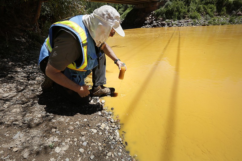 Dan Bender, with the La Plata County Sheriff's Office, takes a water sample from the Animas River near Durango, Colo. after an EPA cleanup team accidentally released 3 million gallons of mine waste into Cement Creek, which flows into the Animas River. (Jerry McBride/The Durango Herald via AP)